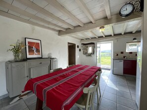Un comedor con una mesa dispuesta para dos, una cocina equipada con lavavajillas y vistas al exterior.