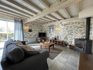 Una sala de estar acogedora con una pared de piedra, chimenea, sofá, televisor y una mesa de centro de madera.