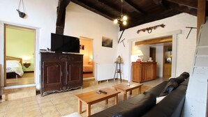 A cozy living room with a wooden sofa, a television on a cabinet, a coffee table, and a fireplace. - Otxania - Juxue - Gîte (JUXUE)