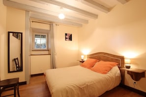 Una camera da letto con un letto, comodini, uno specchio, una finestra e una porta.