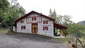 A stone building with a wooden porch and a wooden door. - Otxania - Juxue - Gîte (JUXUE)