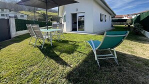 Une maison moderne dotée d’un patio, d’une table à manger avec des chaises et d’un grand parasol.