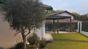 Une maison dotée d’un patio couvert, d’une pelouse et de diverses plantes et fleurs.