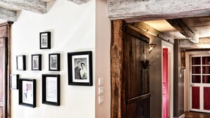 A hallway with framed photographs on the wall and a wooden door with a red handle. - SARAHANDIA - ALDUDES (LES-ALDUDES)