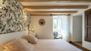 A bedroom with a bed, a chair, a mirror, and a window with curtains. - SARAHANDIA - ALDUDES (LES-ALDUDES)