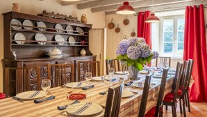 A dining room with a long table set for six, wooden chairs, a wooden buffet with dishes, and a vase of flowers. - SARAHANDIA - ALDUDES (LES-ALDUDES)