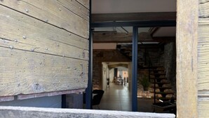 Un mur extérieur en bois avec une porte-fenêtre coulissante donnant sur un couloir doté d’un mur en pierre et d’un escalier.