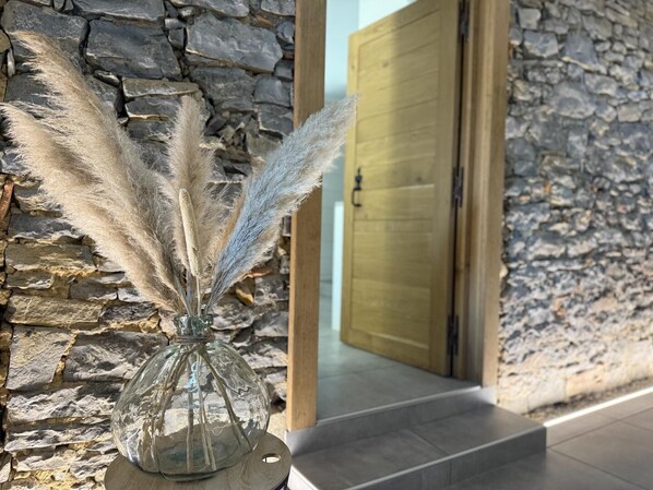 A stone wall with a glass vase containing pampas grass.