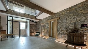 Une pièce spacieuse avec un mur en pierre, un banc en bois, une chaise et un élément décoratif rustique représentant de l’eau.