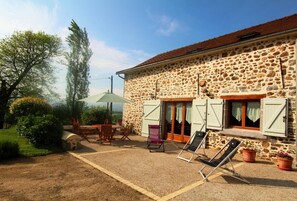 A stone building with a patio area, outdoor furniture, and a view of the surrounding landscape.