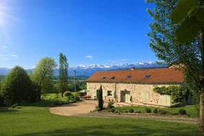A stone house with a red roof, a patio, and a view of snow-capped mountains.
