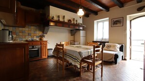 A cozy kitchen with wooden cabinets, a dining table, and a sofa. - Caricaburia - Juxue - Gîte (JUXUE)