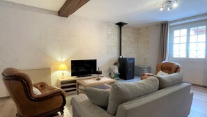 Un salon comprenant un canapé, un fauteuil, un téléviseur, une cheminée et une fenêtre.