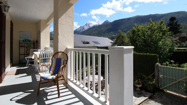 Un balcon avec vue sur les montagnes, une chaise et une table.