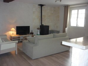 A living room with a sofa, a television, a fireplace, and a window.