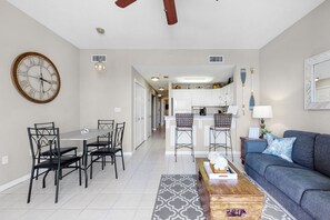 A modern living room with a sofa, coffee table, and dining area with chairs and a table.