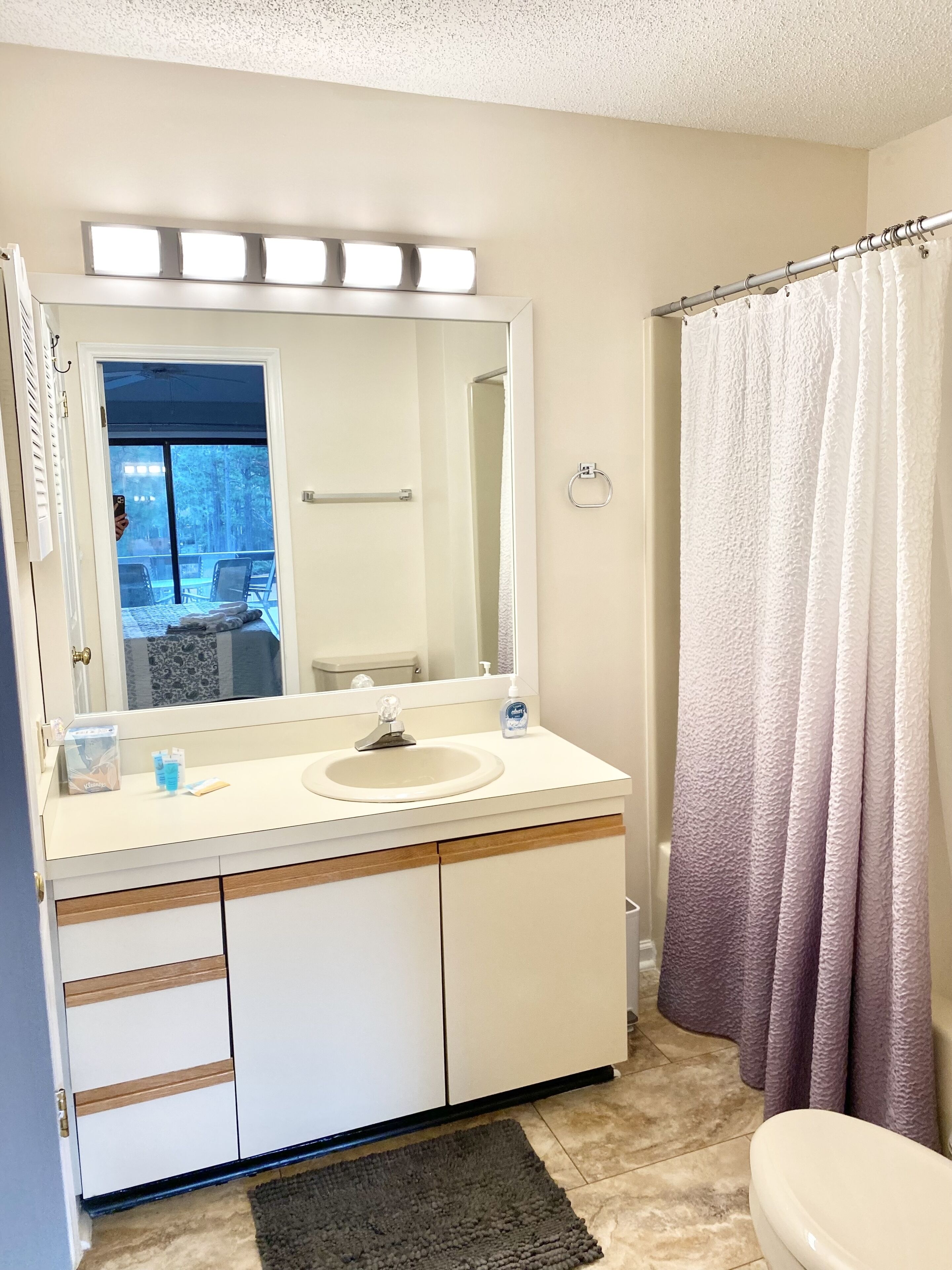 A bathroom with a sink, mirror, and shower curtain.