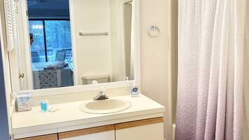 A bathroom with a sink, mirror, and shower curtain.