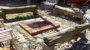 Un espacio exterior rústico con un banco de madera, una parrilla de metal y una decoración de calabaza grande.