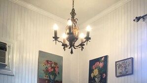 Un comedor con una mesa de vidrio, dos sillas moradas, una araña y pinturas florales en las paredes.