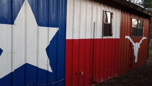 Un edificio de metal corrugado con una gran estrella blanca a la izquierda y un diseño rojo y blanco a la derecha, que recuerda a la bandera del estado de Texas.