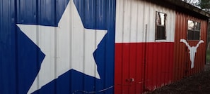 A corrugated metal building with a large white star on the left and a red and white design on the right, resembling the Texas state flag.
