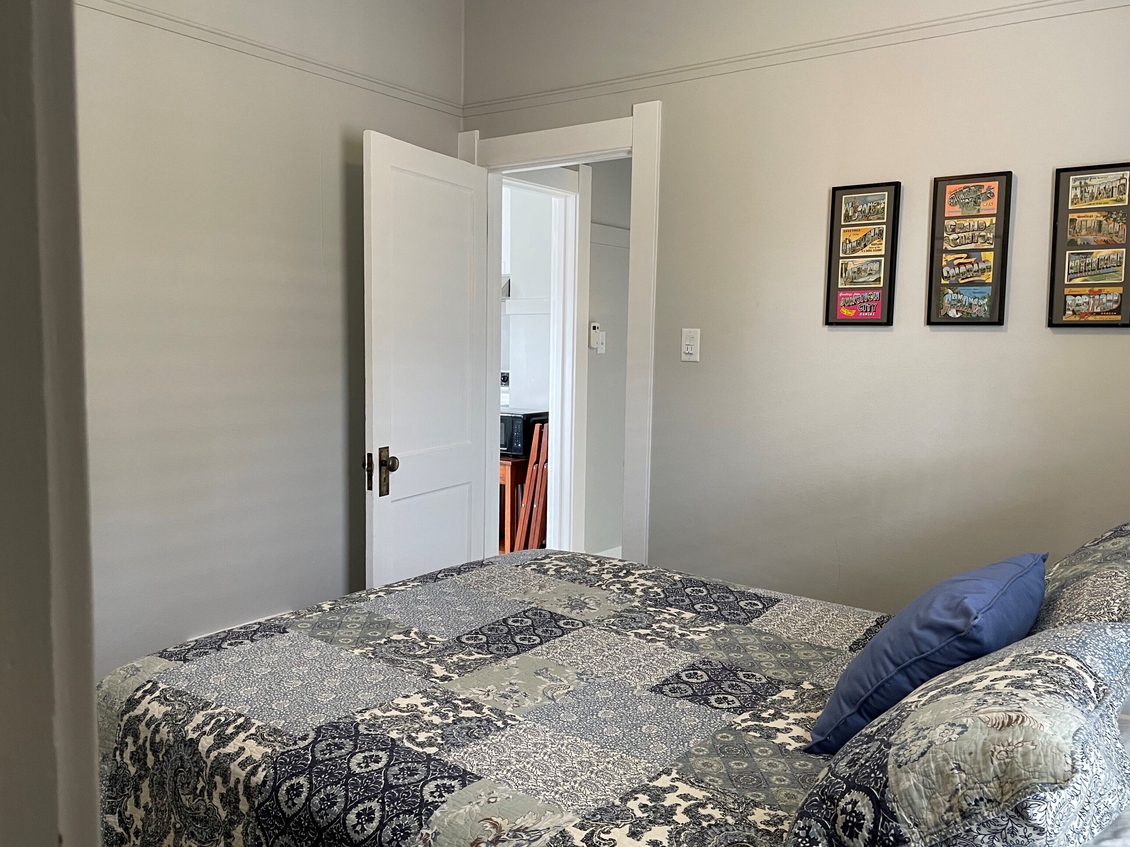 Ein Schlafzimmer mit einem Bett, einer Tür und einer Wand mit gerahmten Bildern.