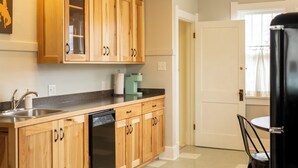 A kitchen with wooden cabinets, a dishwasher, and a coffee maker. - Historic Home Near Downtown & UW (Laramie)