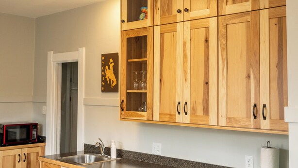 A kitchen with wooden cabinets, a stainless steel sink, and a microwave. - Historic Home Near Downtown & UW (Laramie)