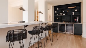 A modern kitchen with a white countertop, black bar stools, and a black shelving unit with kitchenware. - Dupont Circle Embassy Inn by FOUND (Washington)