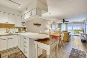 Relax in a spacious living area with a curved dining table, comfortable sofa, and sliding glass doors leading to an outdoor space.