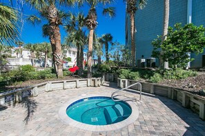 Relax by the pool surrounded by lush greenery and palm trees, with a brick pathway and metal ladder for easy access.