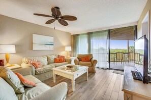 Relax in this stylish living room with a sofa set, coffee table, and large ceiling fan.