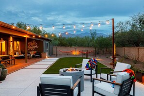 Un patio exterior con un brasero, asientos e iluminación colgante.