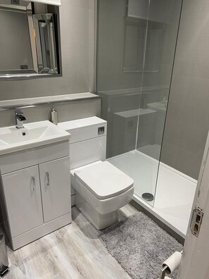 Un baño moderno con lavamanos, inodoro y ducha blancos.