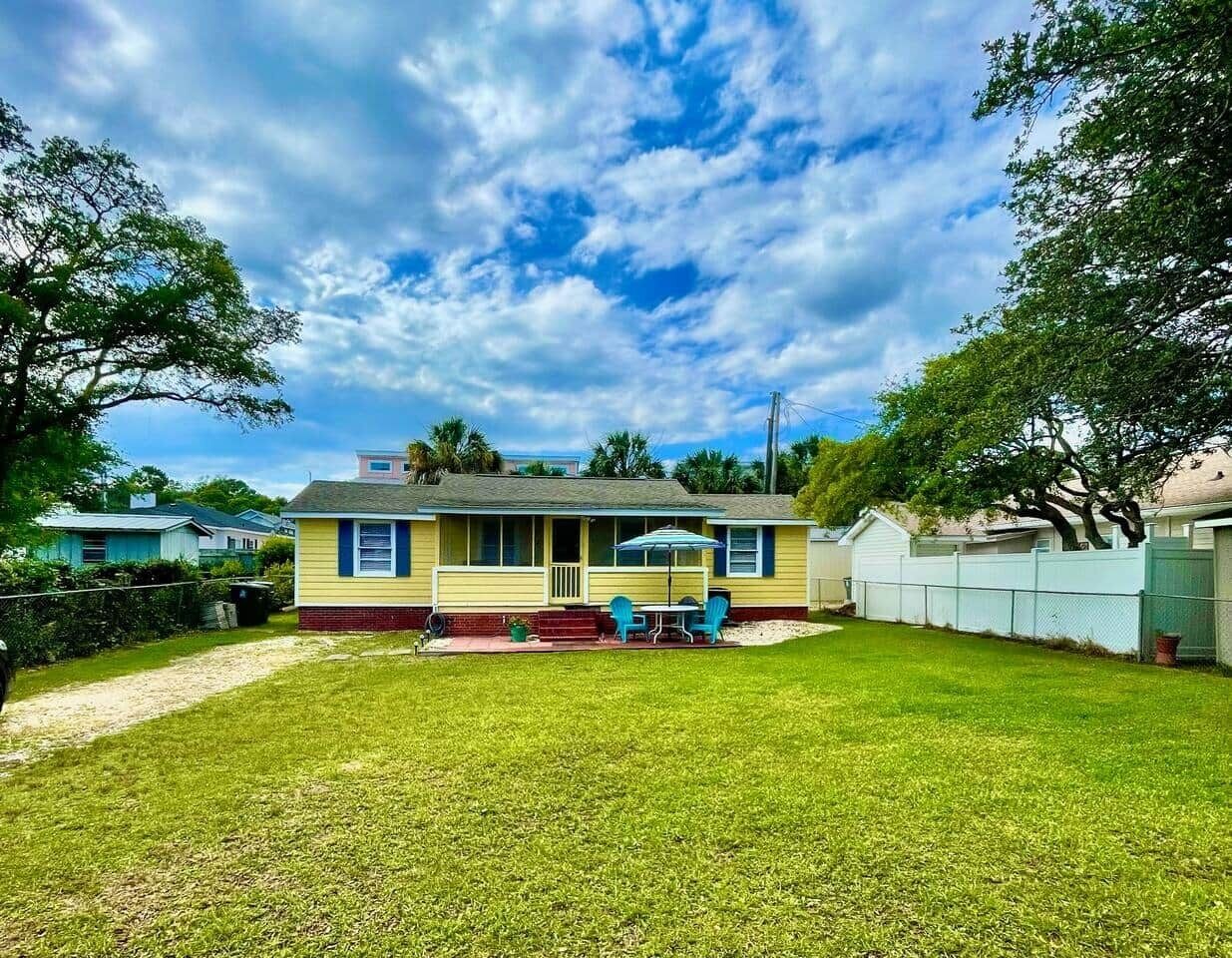 A single-story house with a front porch, a small patio, and a fenced yard.