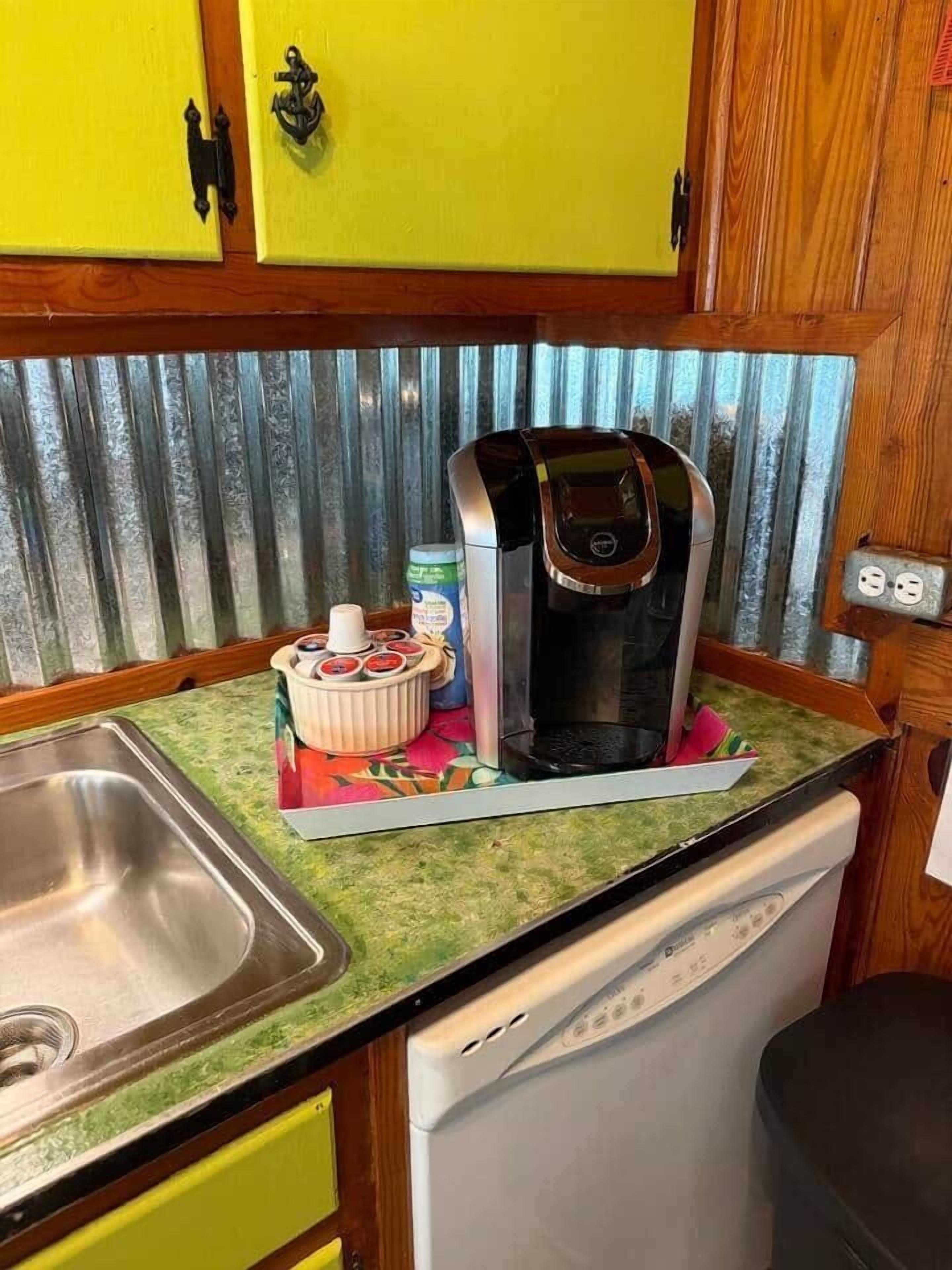 Et lille køkken med kaffemaskine, vask og opvaskemaskine.