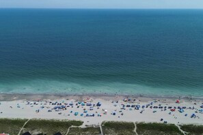 A beach with numerous umbrellas and people, indicating a popular tourist spot.