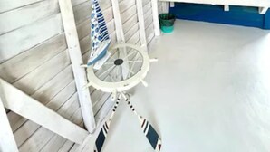 Quarto com paredes de madeira branca, uma parede em azul, pia branca e ventilador de teto.
