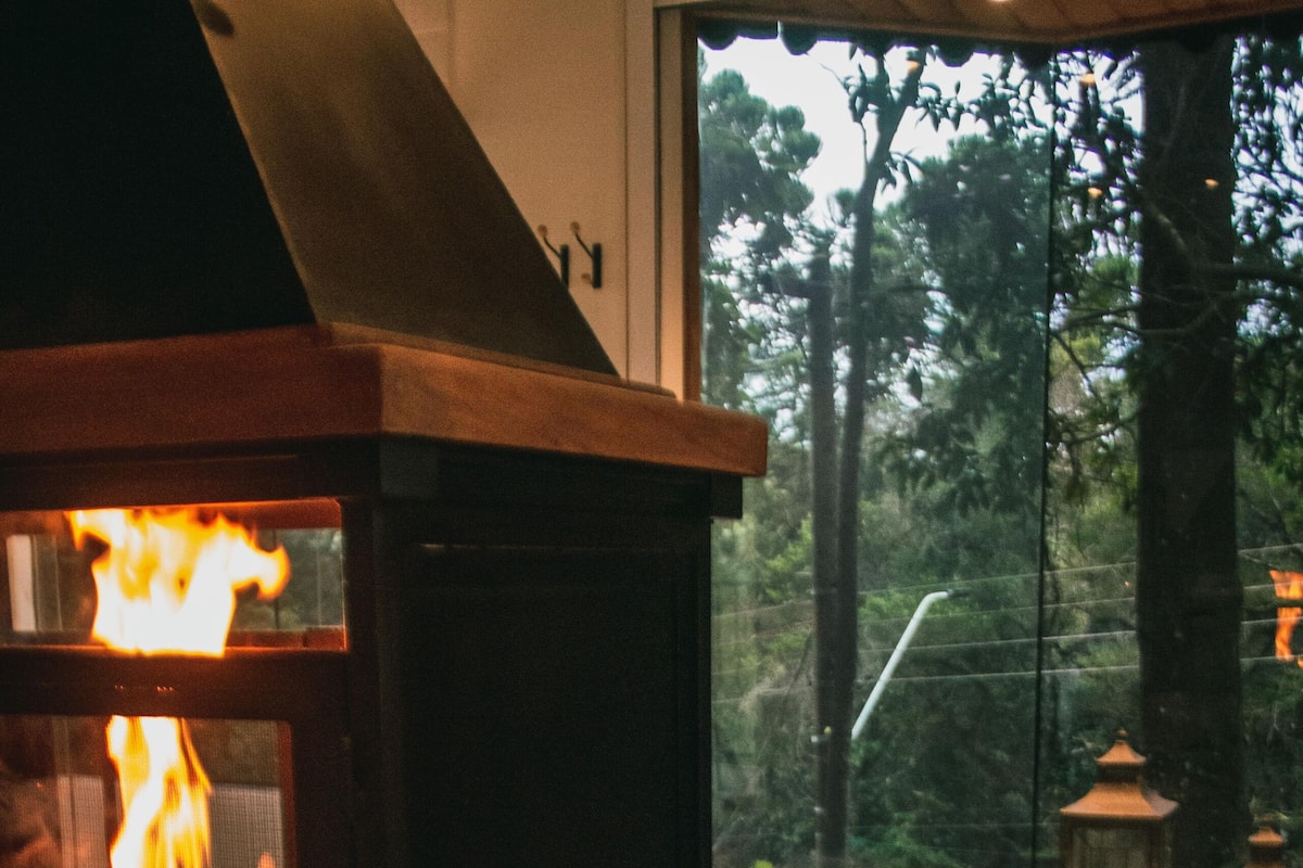 Une cheminée en pierre avec un feu visible, un mur en pierre et un jacuzzi dans lequel une personne est assise.