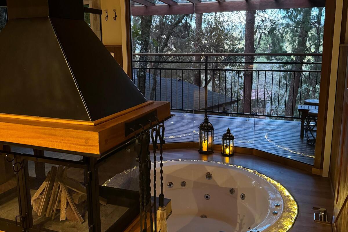 Un espace intérieur accueillant avec un poêle à bois, un bain à remous et une terrasse dotée de meubles d’extérieur.