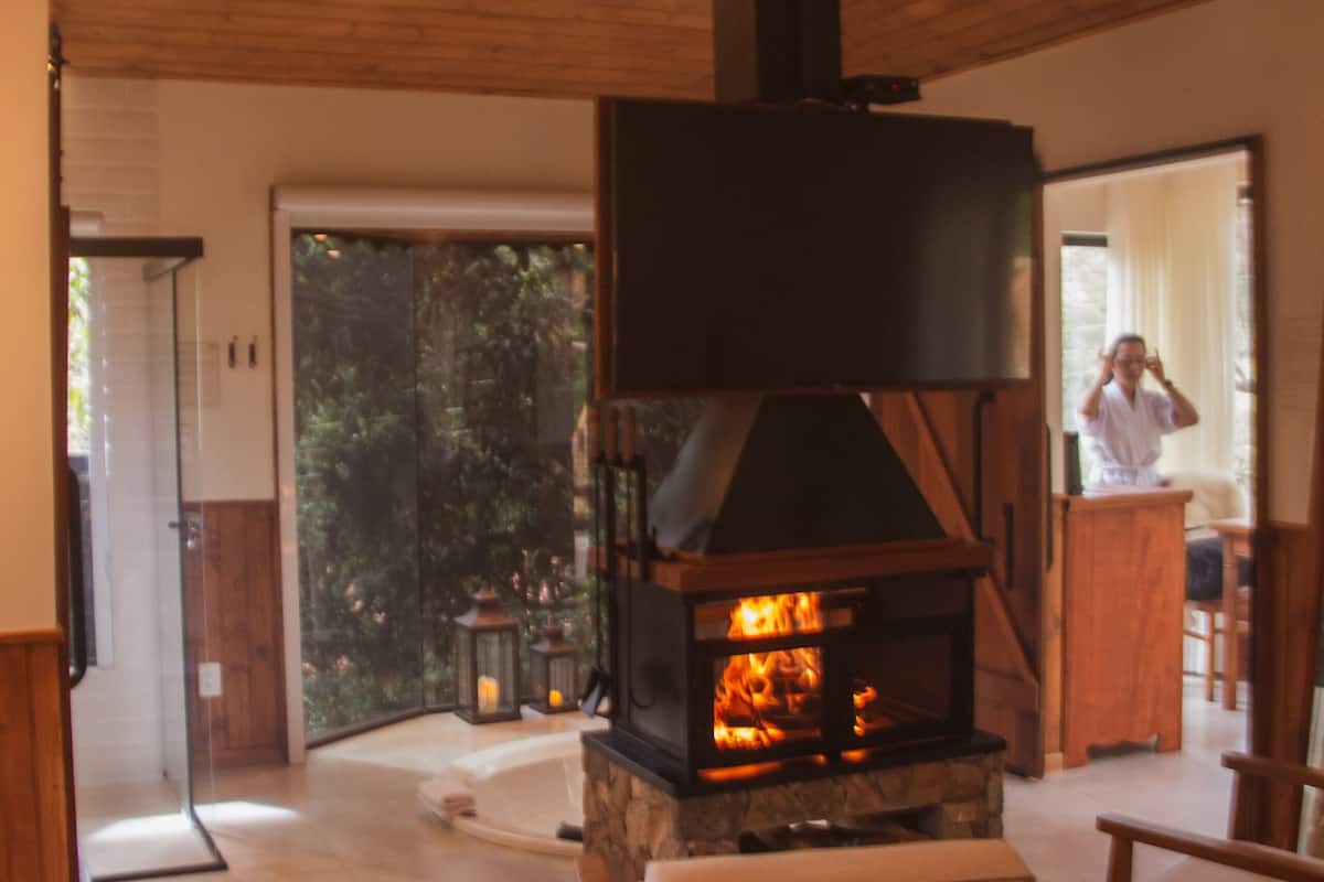 Une pièce dotée d’une cheminée, d’un plafond en bois et offrant une vue à travers une porte vitrée.