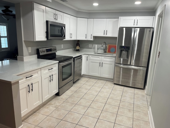 A modern kitchen with white cabinetry, stainless steel appliances, and a tiled floor. - Pool, Central location, 2026 Remodel. (Tampa)