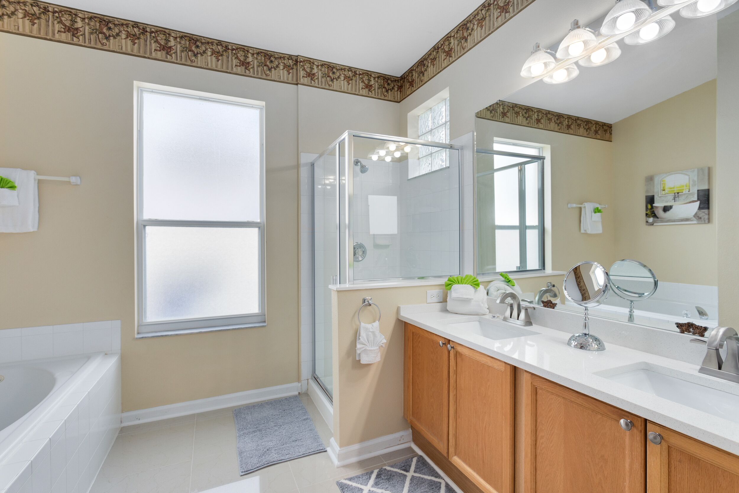 A modern bathroom with a glass shower enclosure, a bathtub, wooden cabinets, and a large mirror.