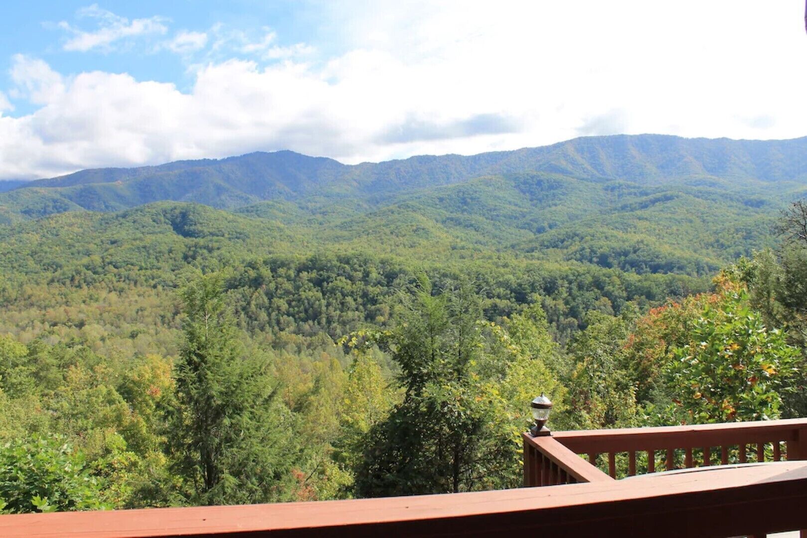 A view from a balcony overlooking a forested mountain range.
