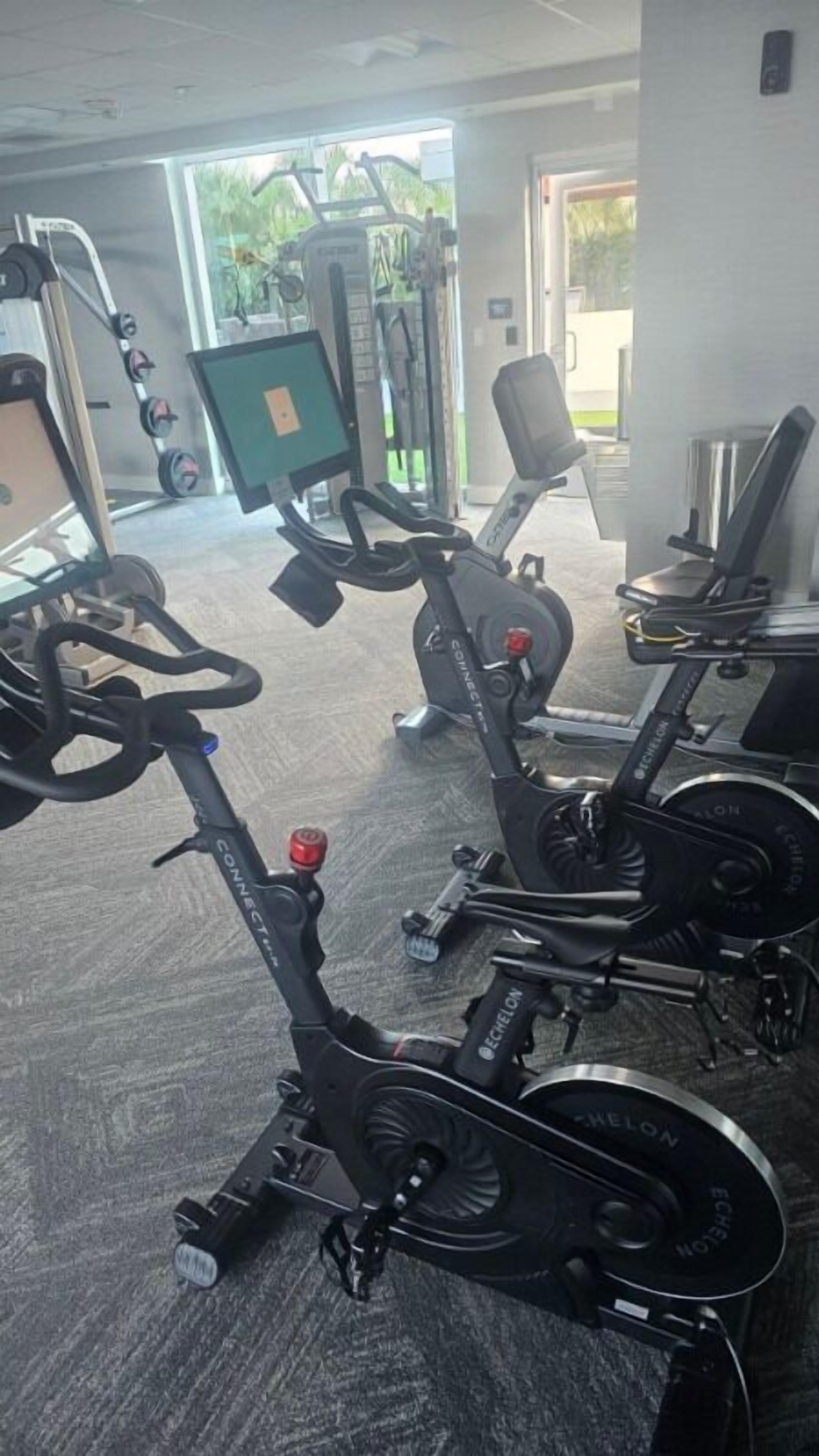 Un gimnàs amb bicicletes estàtiques, aparells de musculació i equip per a exercicis cardiovasculars.