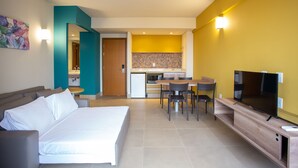 A modern hotel room with a bed, a sofa, a dining table with chairs, a kitchen area, and a TV. - Solar das Águas Park Resort - Olimpia SP (Olímpia)