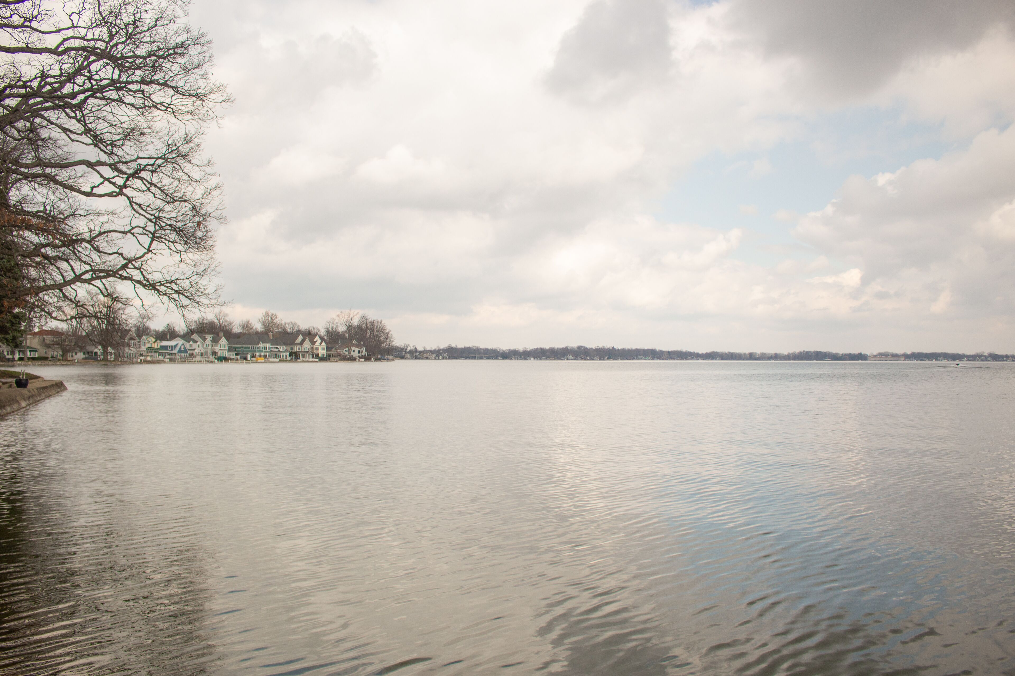 A calm lake with a row of houses along the shore.
