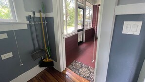 Un couloir doté d’un plancher en bois, d’un balai, d’une serpillière et d’une fenêtre donnant sur l’extérieur.
