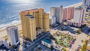 A coastal hotel with multiple high-rise buildings, a parking area, and a beach view. - The Pink Flamingo | Bold & Vibrant By The Beach (Myrtle Beach)